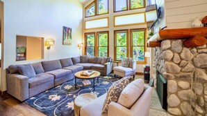 A spacious living room with a sectional sofa, a round coffee table, and a stone fireplace. - Pet Friendly 2+L/3BA W/ Views! Jacuzzi, W/D & BBQ (Mammoth Lakes)
