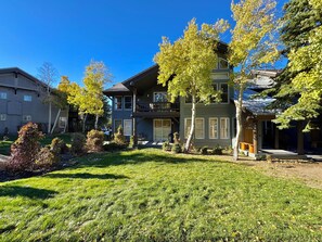 A two-story residential building with a balcony, surrounded by well-maintained lawns and trees. - Pet Friendly 2+L/3BA W/ Views! Jacuzzi, W/D & BBQ (Mammoth Lakes)