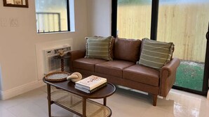 Uma sala de estar com um sofá de couro marrom, dois almofadas, uma mesa de centro e um livro.