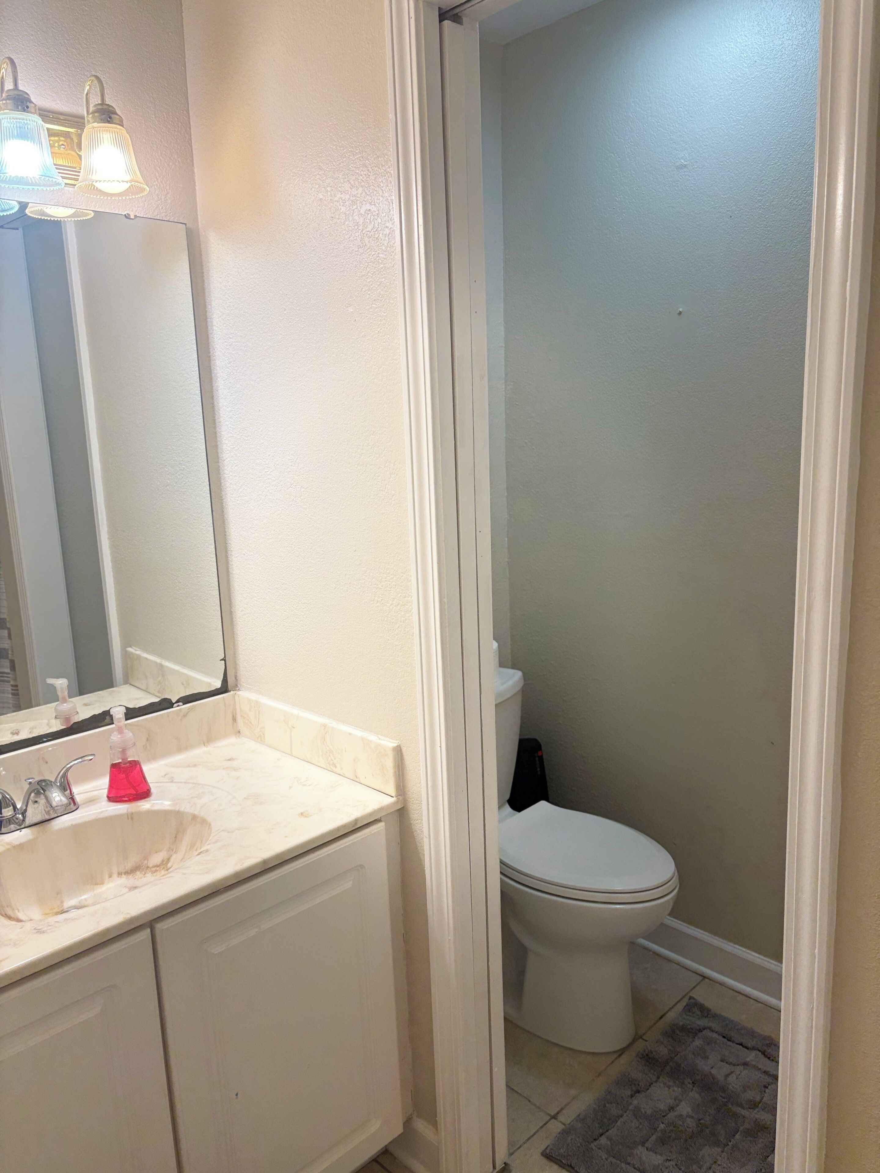 A bathroom with a white sink, mirror, and toilet.