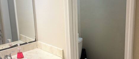 A bathroom with a white sink, mirror, and toilet.