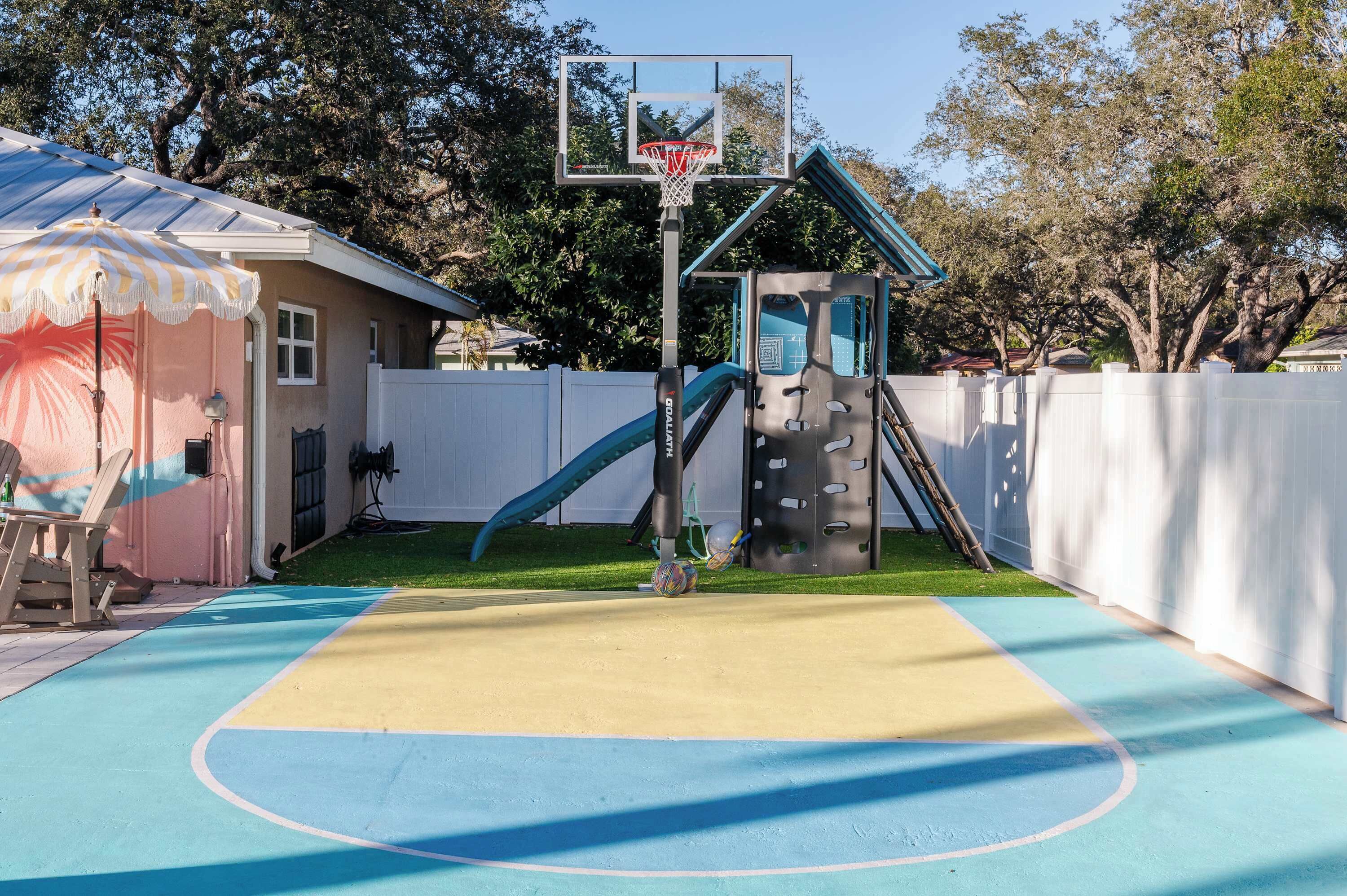 A basketball court with a hoop, a slide, and a climbing wall.