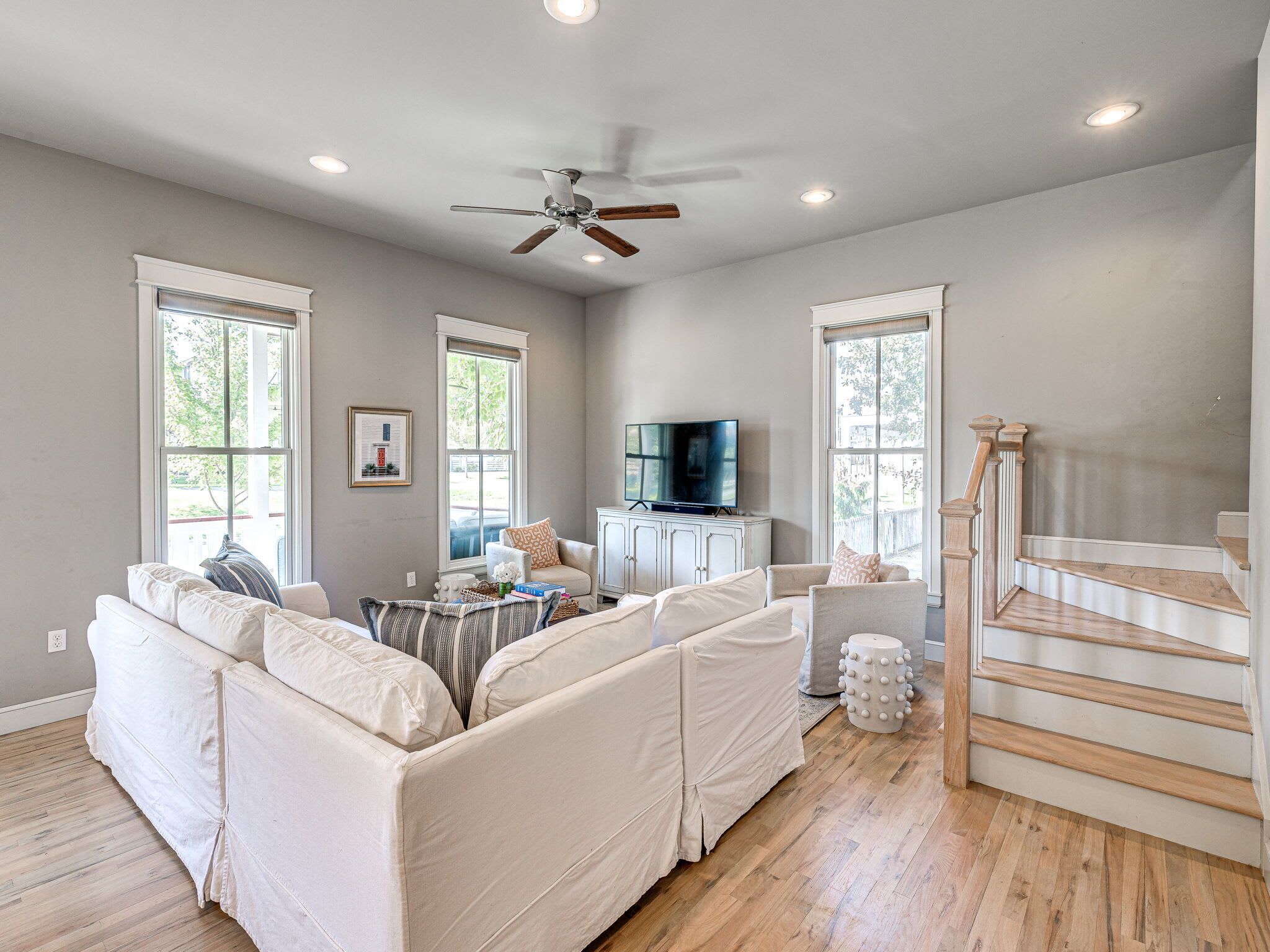 A spacious living room with a large sectional sofa, a television, and a staircase.