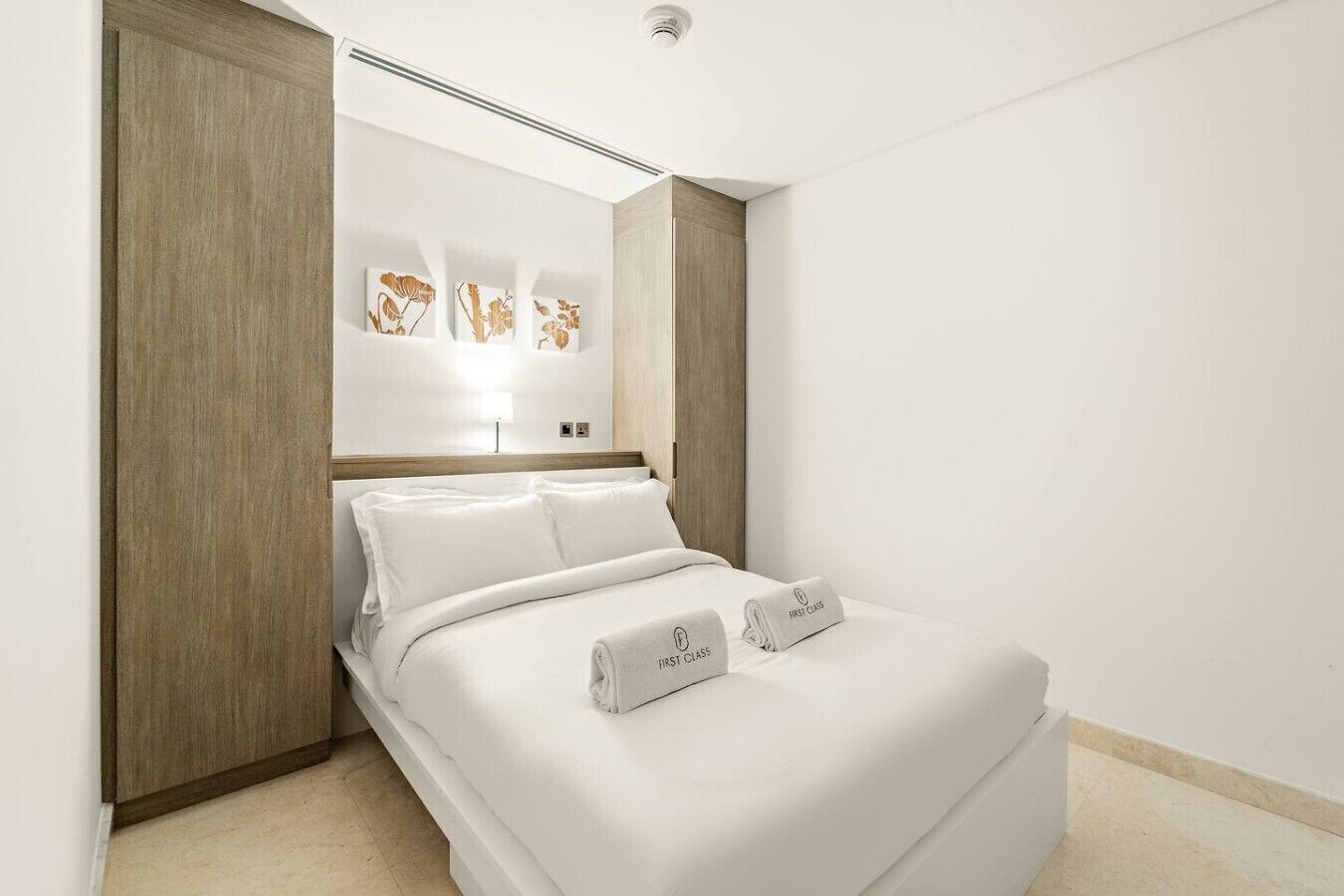 Ein modernes Hotelzimmer mit einem großen Bett, Holzvertäfelung und Kunstwerken an der Wand.