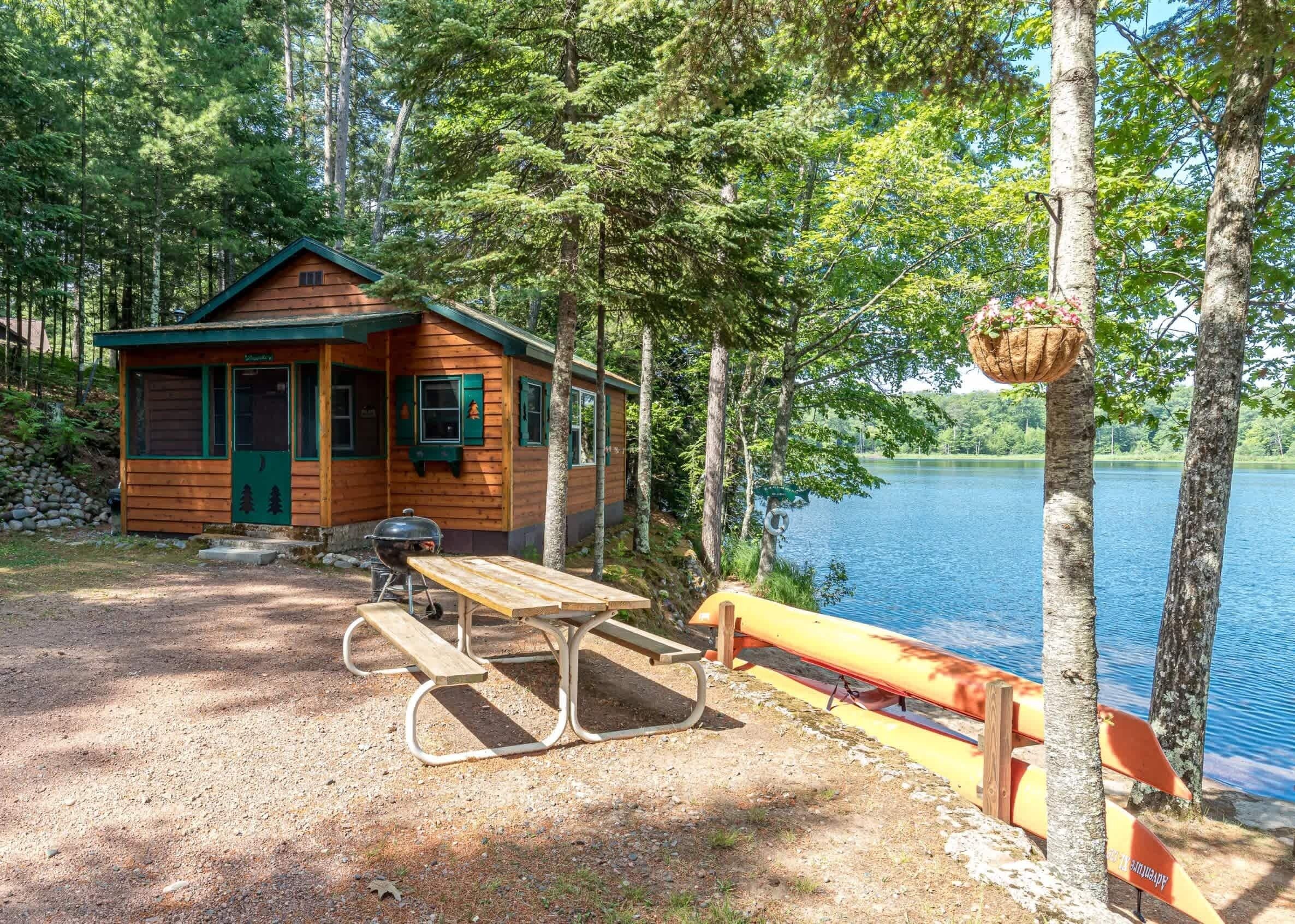 Una cabana de fusta amb taula de pícnic i bancs al costat d'un llac.