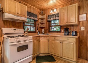 A wooden cabin kitchen with a white stove, wooden cabinets, and a coffee maker. - Bouchard Shores Resort - Your Private Northwoods Getaway (Minocqua)