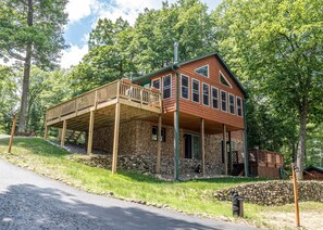A two-story cabin with a stone foundation, a wooden deck, and a stone wall. - Bouchard Shores Resort - Your Private Northwoods Getaway (Minocqua)