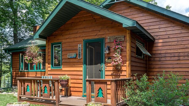 A wooden cabin with a porch, a welcome sign, and a sign indicating it's a campsite. - Hilltop - Bouchard Shores Resort (Minocqua)