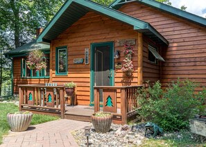 A wooden cabin with a porch, a welcome sign, and a sign indicating it's a campsite. - Hilltop - Bouchard Shores Resort (Minocqua)