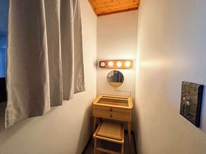 Ein kleines Badezimmer mit Waschtisch, Spiegel und einer Leuchte.