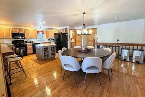 A spacious kitchen with wooden cabinets, a central island, and a dining area with four chairs. - Hilltop - Bouchard Shores Resort (Minocqua)