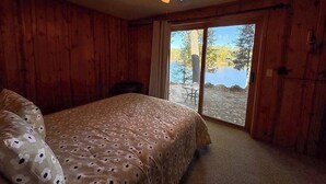 A bedroom with a bed, a ceiling fan, and a view of a lake through a sliding glass door. - Hilltop - Bouchard Shores Resort (Minocqua)