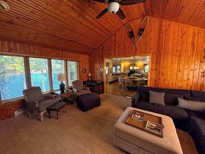 A cozy cabin interior with a wooden interior, a dining area, and a living room with a sofa and armchairs. - Hilltop - Bouchard Shores Resort (Minocqua)
