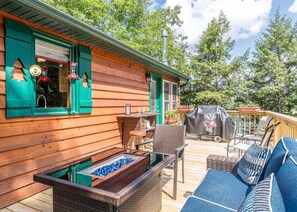 A wooden deck with outdoor furniture, a barbecue grill, and a glass-top table with blue stones. - Hilltop - Bouchard Shores Resort (Minocqua)