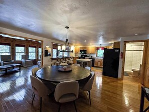 A spacious kitchen with wooden floors, a central island, and a dining area with a round table and chairs. - Hilltop - Bouchard Shores Resort (Minocqua)