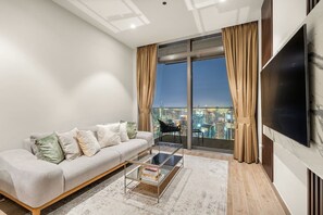 Un salon moderne avec un canapé, une table basse et un grand téléviseur.