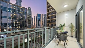 A balcony with a city view, a small table with chairs, and potted plants.