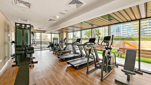A modern gym with treadmills, elliptical machines, and weight benches.