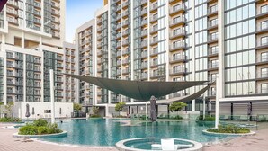 A modern residential building with a swimming pool and a covered area.