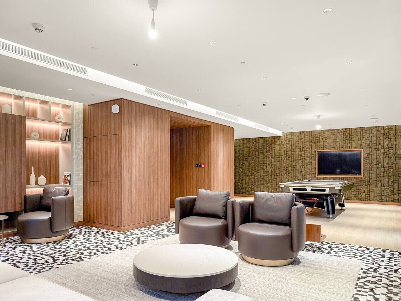 Un vestíbul d'hotel modern amb sofàs de cuir, billar i televisió de pantalla plana.