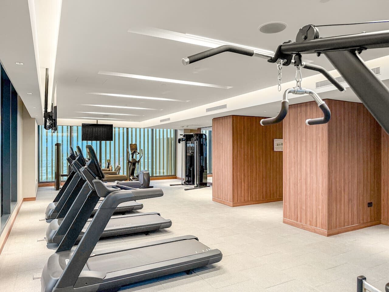 Ein modernes Fitnessstudio mit Laufbändern, Krafttrainingsgeräten und einem großen Spiegel.