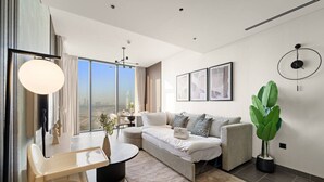 A modern living room with a sofa, a dining table, and a large window offering a city view.