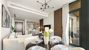 A modern dining area with a round table set for four, a sofa, and a large window with curtains.