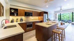 Une cuisine moderne avec des meubles en bois, un îlot central et un coin repas offrant une vue sur la verdure.