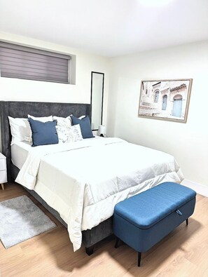 A bedroom with a bed, bedside table, bench, and a framed picture on the wall. - Kickback & relax in a cozy & stylish home in Moncton (Moncton)