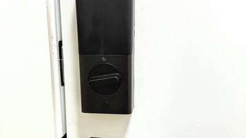 Uma porta com fechadura eletrônica preta e puxador.