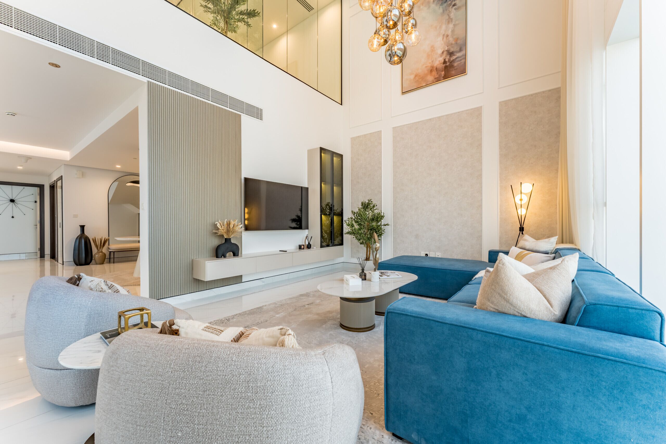 Una sala de estar moderna con un sofá azul, sillones grises y una mesa de centro redonda.