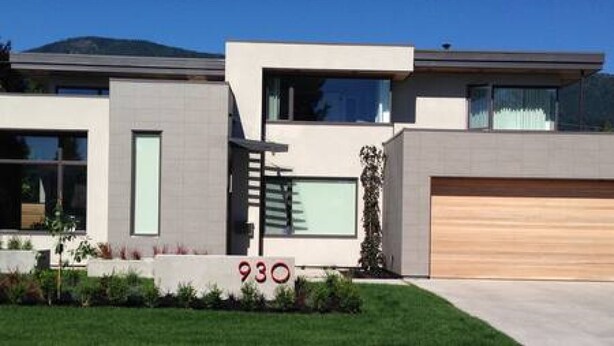 Une maison moderne à deux étages, dotée d’un garage, de grandes fenêtres et d’une pelouse bien entretenue.