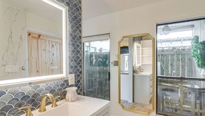 A bathroom with a white sink, gold faucets, and a large mirror. - Shop & Explore: Duplex Unit 8 Mi to NRG Stadium! (Houston)