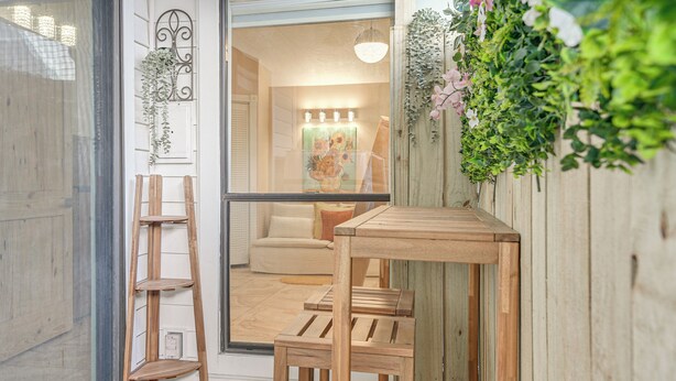 A wooden outdoor seating area with a table and chairs, a wooden ladder, and a hanging plant. - Shop & Explore: Duplex Unit 8 Mi to NRG Stadium! (Houston)
