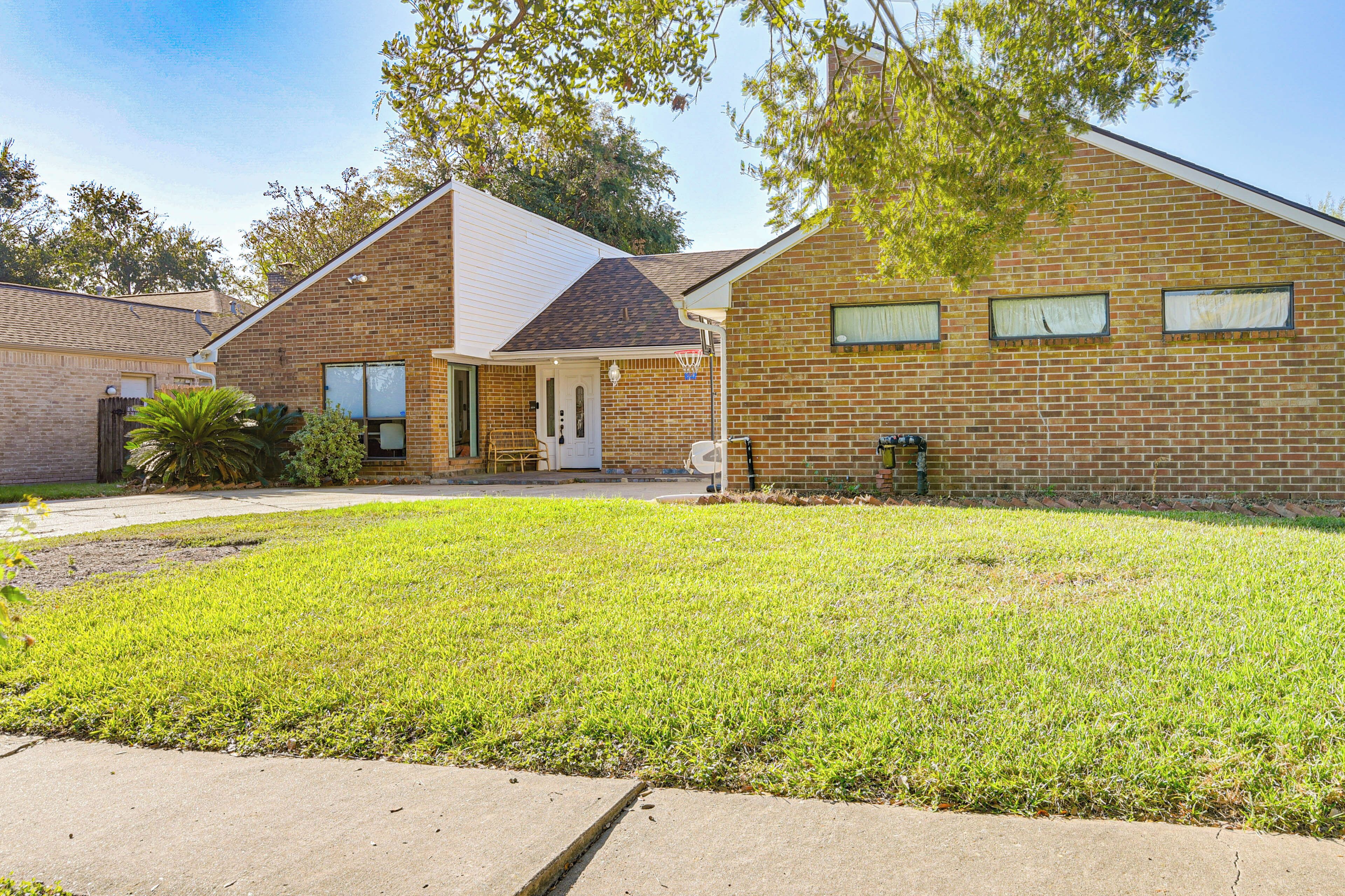 A two-story brick house with a front porch, a small front yard, and a mailbox.