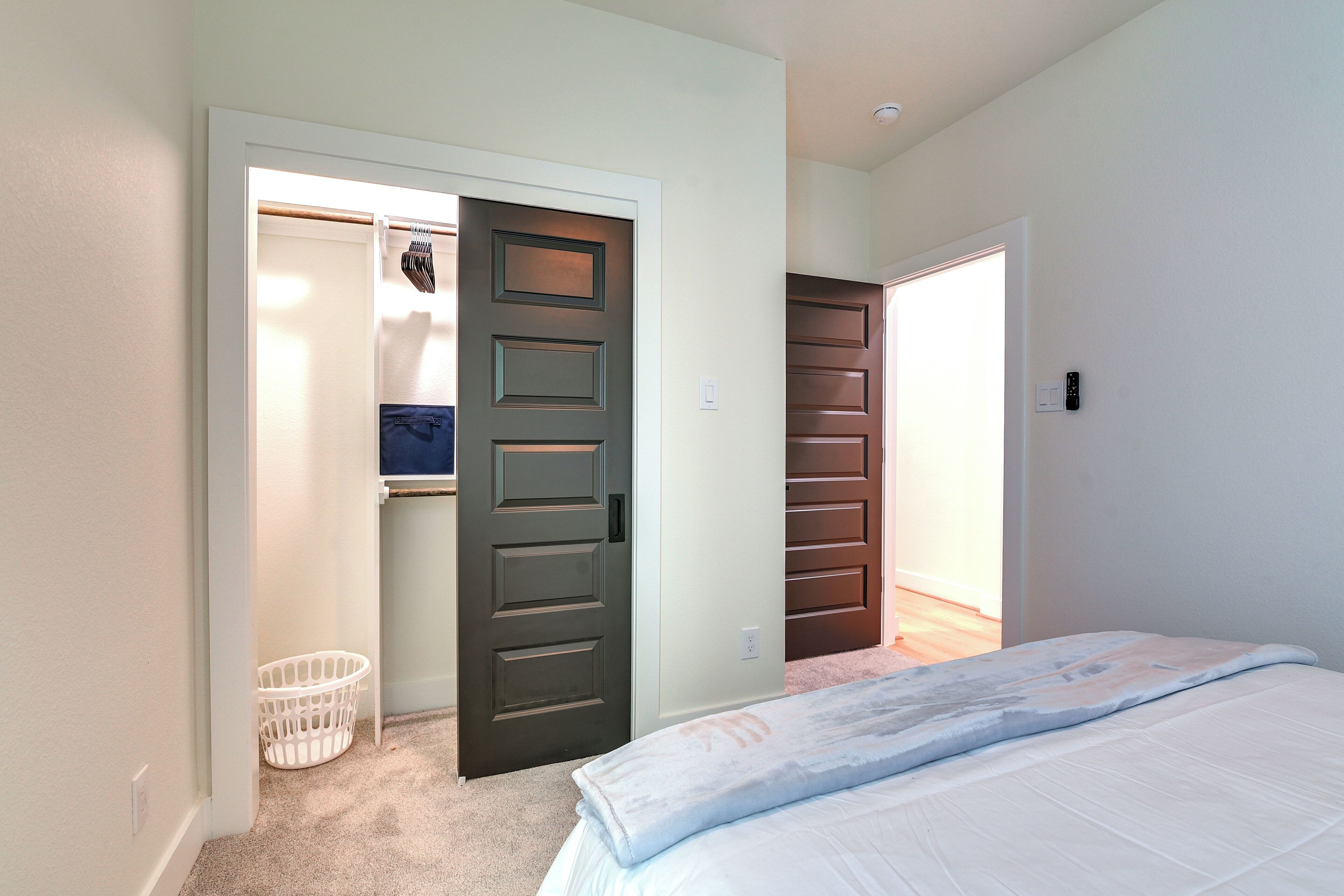 Een slaapkamer met een bed, een kast en een wasmand.