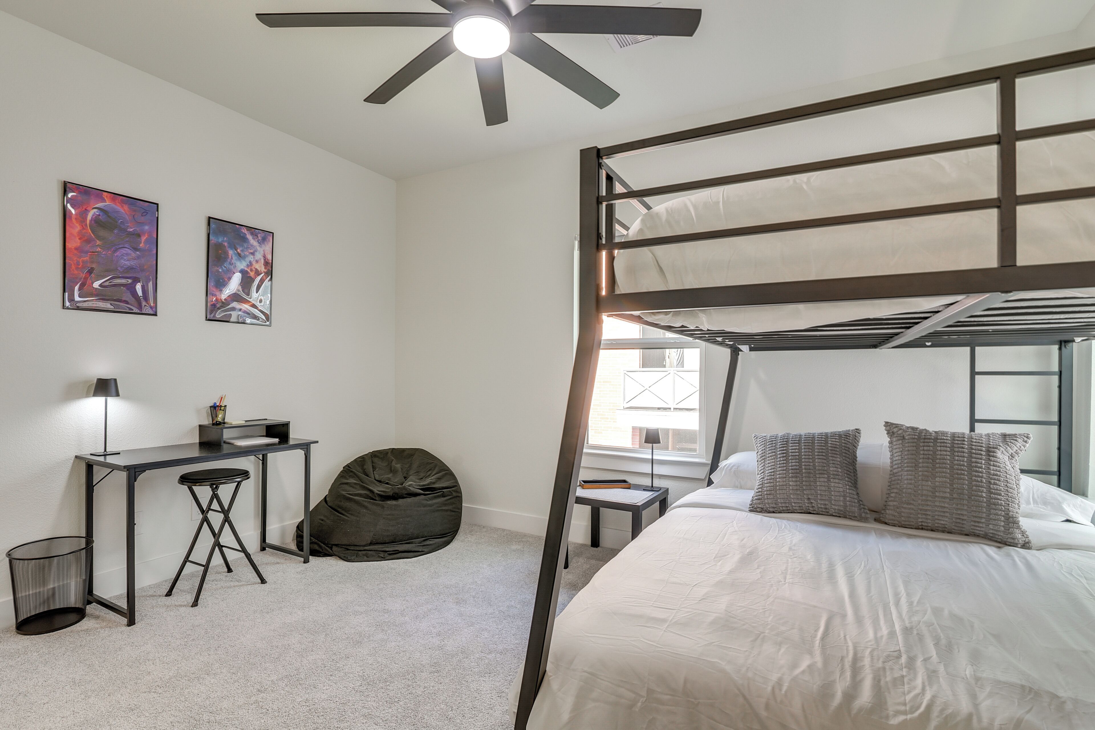 A bunk bed room with a desk, chair, and bean bag.
