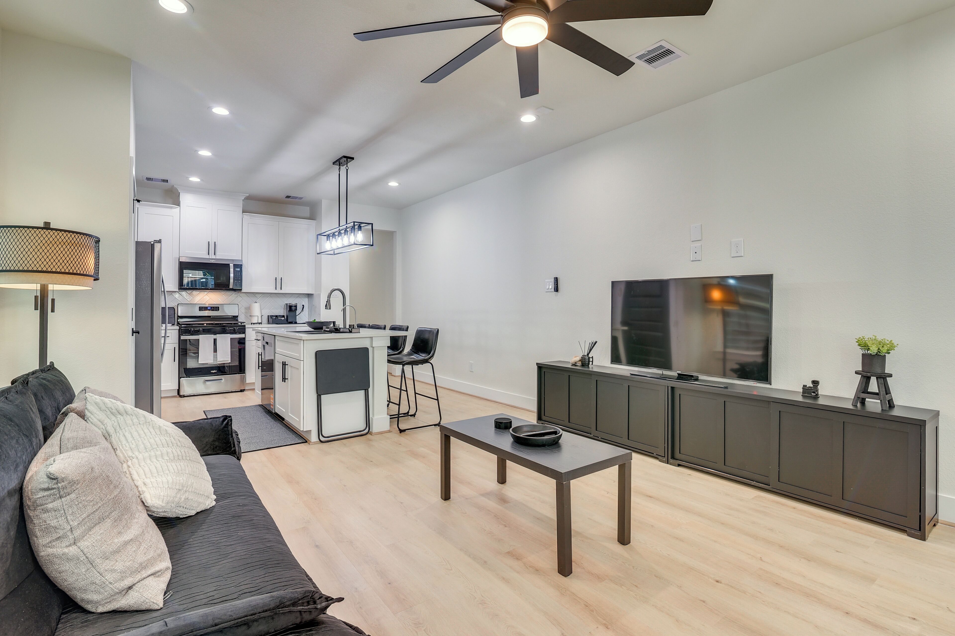 Una cocina moderna con una isla central, un comedor con mesa y sillas, y una sala de estar con sofá.