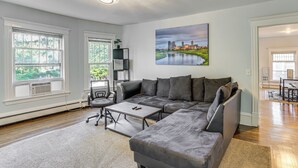 A modern living room with a sectional sofa, a coffee table, and a painting of a cityscape. - 2 Mi to Dtwn! Walkable Minneapolis Apt w/ Deck (Minneapolis)