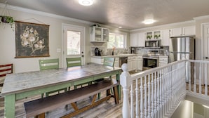 A kitchen with white cabinets, a stainless steel refrigerator, and a dining area with a bench. - 2 Mi to Gardner Village: Family Gem w/ Fenced Yard (West Jordan)
