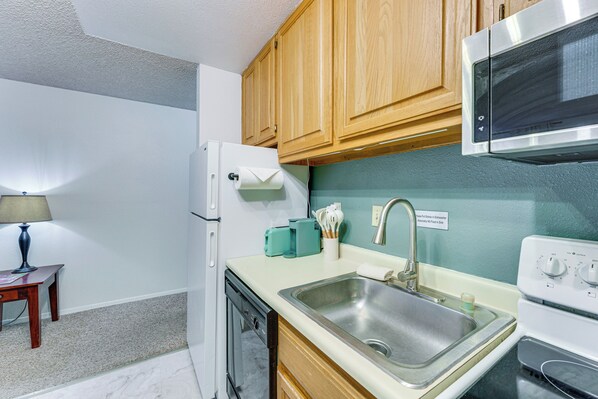 A compact kitchen with wooden cabinets, a stainless steel sink, a microwave, and a dishwasher. - Easy Red River Ski Access! Outdoor Adventure Condo (Red River)