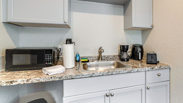 A kitchen with white cabinets, a granite countertop, a stainless steel sink, a microwave, a coffee maker, and a toaster. - Anglers Dream: Studio 2 Mi to 7 Sisters Springs! (Homosassa)