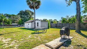 A backyard with a small white shed, a covered grill, and a concrete pathway. - Sleek Studio Bunk 2 Mi to Chassahowitzka River! (Homosassa)