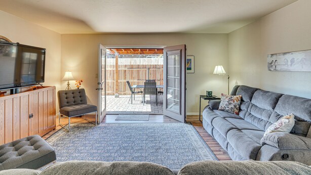 A living room with a sofa, a television, a wooden cabinet, and a dining area with a table and chairs. - 5 Mi to Dtwn: Tucson Townhome w/ Pool Access! (Tucson)