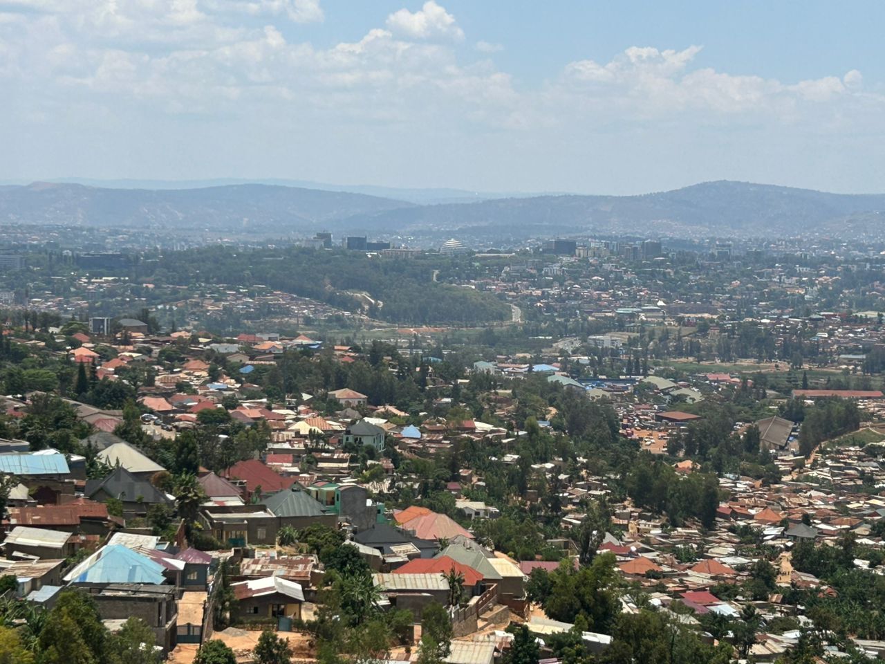 A densely populated urban area with numerous buildings and a hilly backdrop.