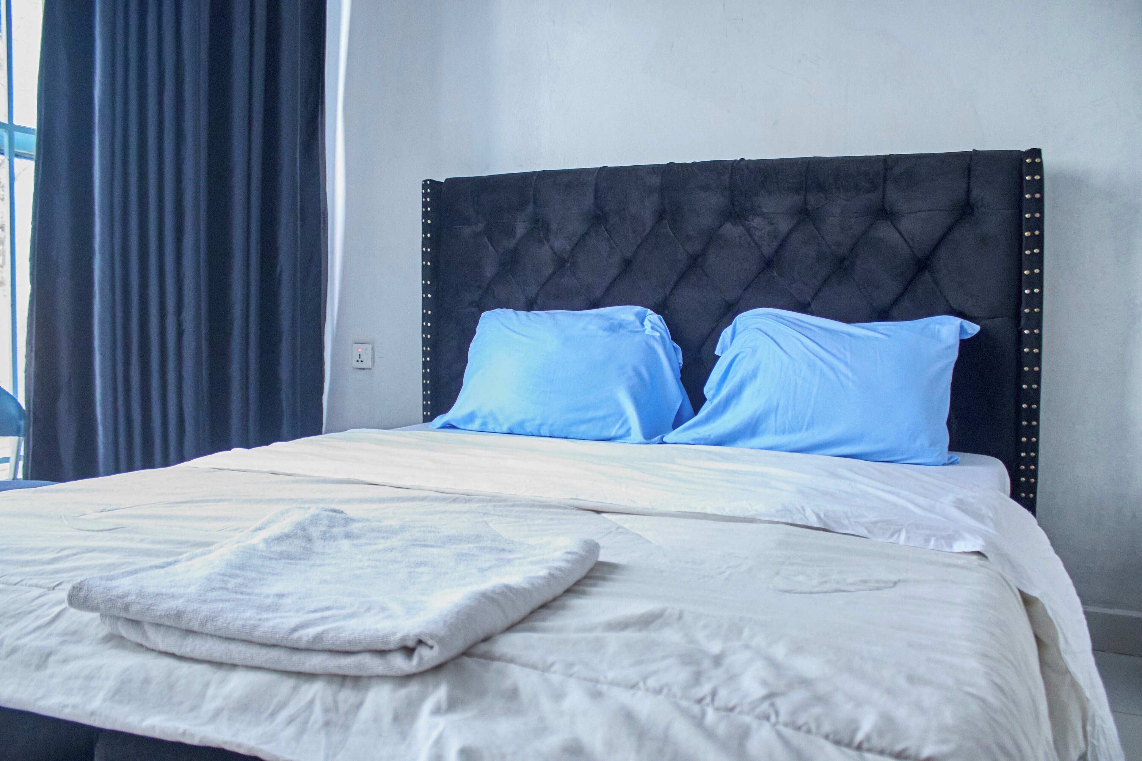 A neatly made bed with a tufted headboard, two pillows, and a folded blanket.