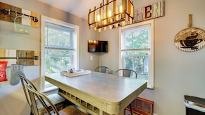 A dining area with a wooden table and chairs, a television mounted on the wall, and a sign that reads "COFFEE". - Little Woodland Home: Hidden Gem By Dtwn Bethlehem (Bethlehem)