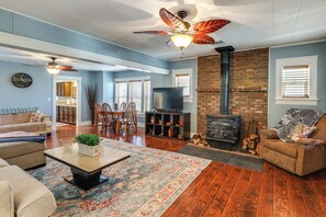 A living room with a fireplace, a ceiling fan, and a television. - Route 66 Retreat: Dog-friendly Home in Williams (Williams)