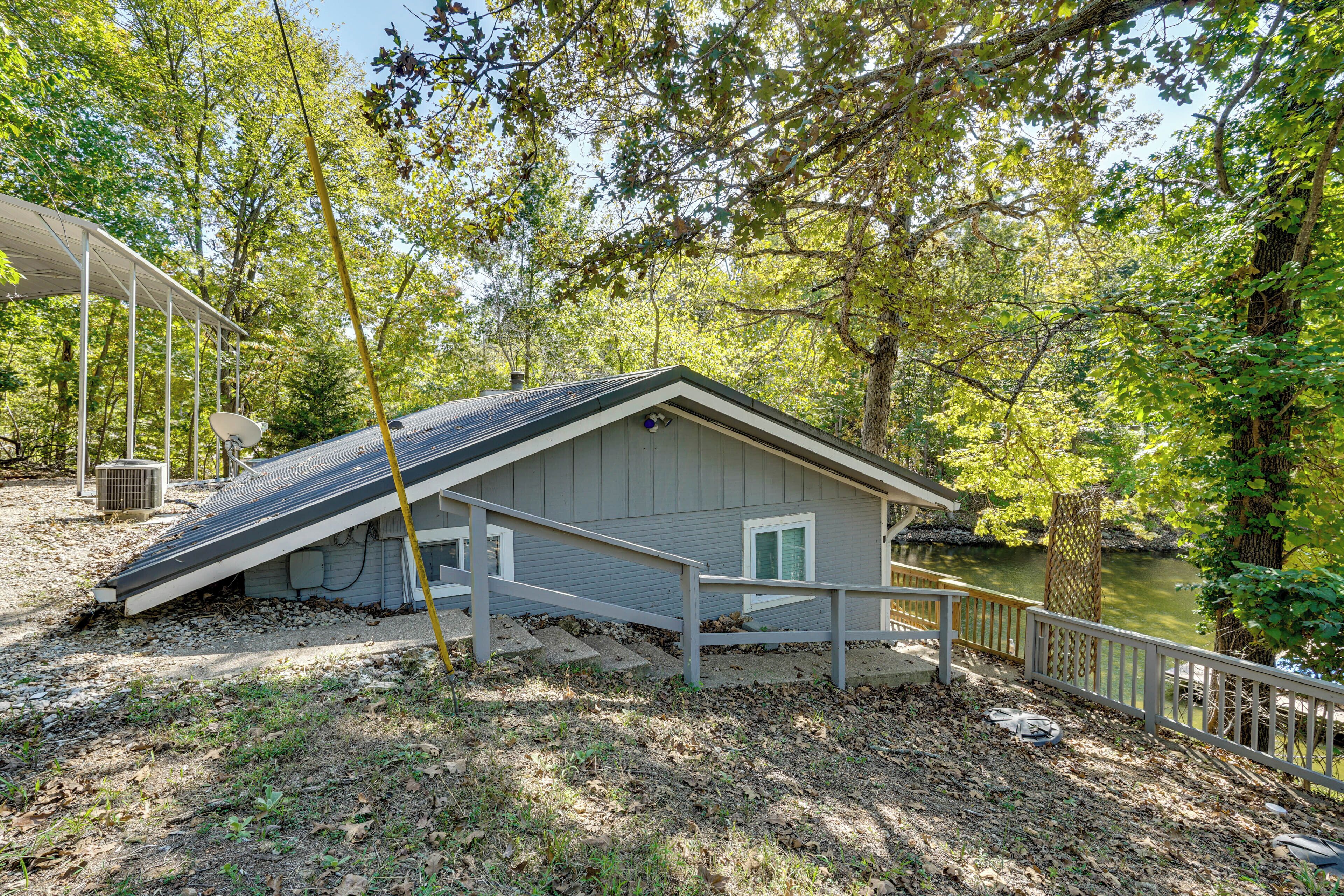 A cabin with a sloped roof, a covered porch, and a view of a pond.