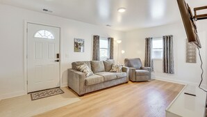 Ein Wohnzimmer mit Sofa, Sessel und Flachbildfernseher.